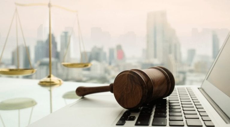 judge gavel on computer with scales of justice on desk of lawyer